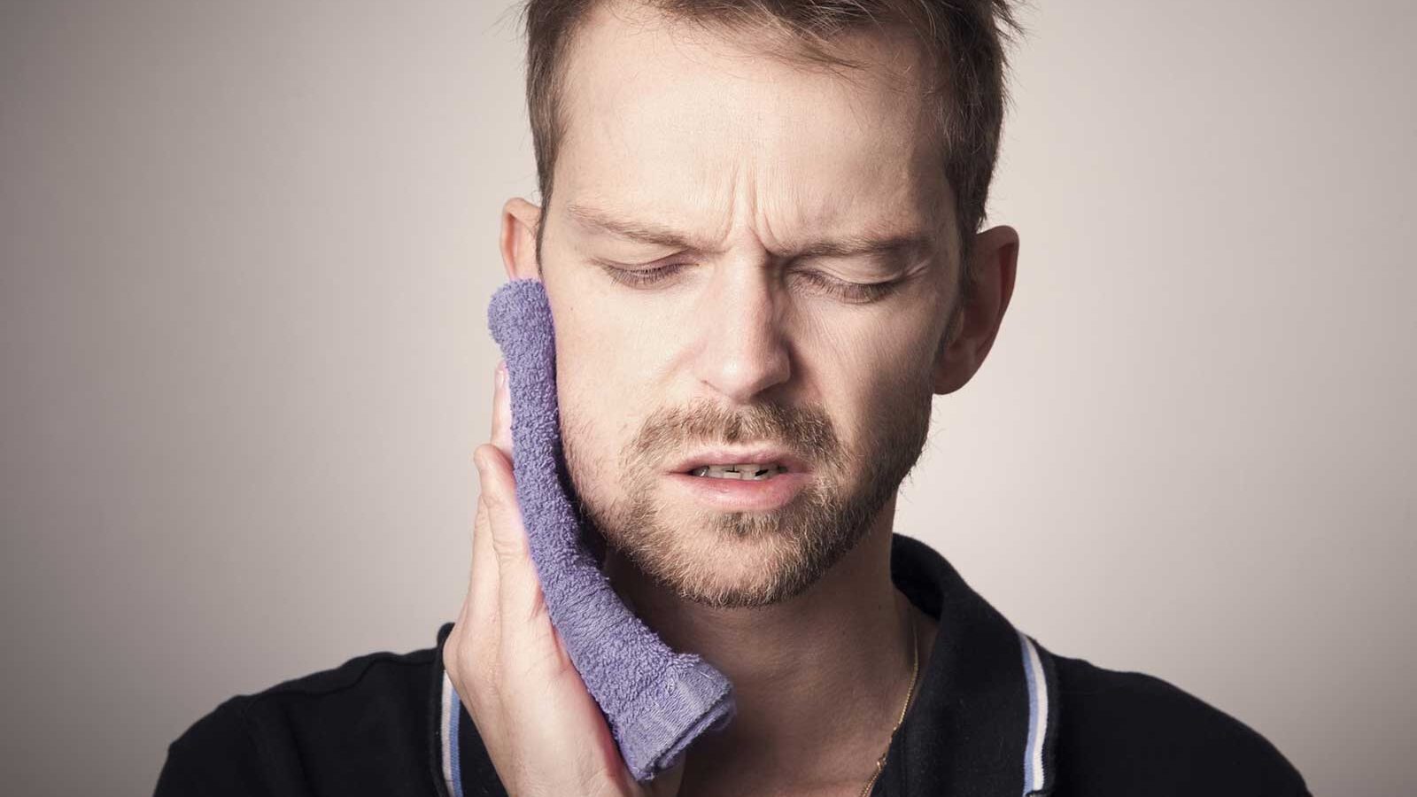 Patient resting with a cold compress after wisdom tooth surgery